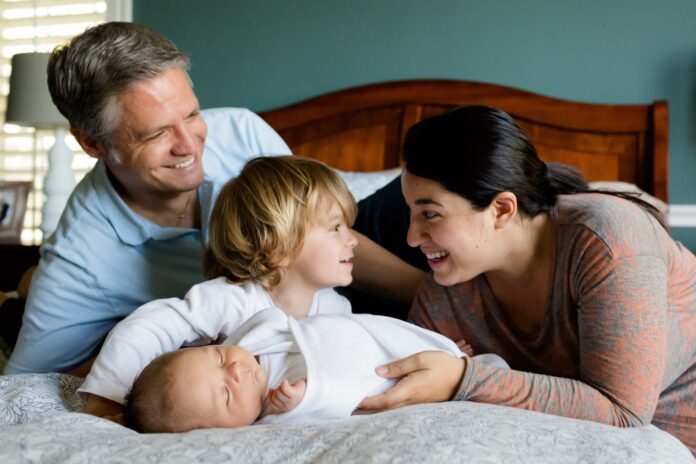 Eine Familie mit zwei kleinen Kindern kuschelt in einem großen Bett