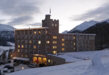 Castell – Die feine Art zu entspannen in Graubünden Großes erleuchtetes Gebäude in der Dämmerung, umgeben von Schnee