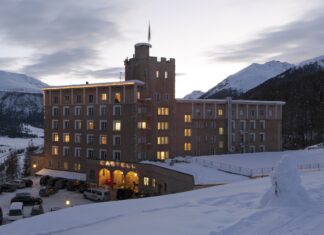 Castell – Die feine Art zu entspannen in Graubünden Großes erleuchtetes Gebäude in der Dämmerung, umgeben von Schnee