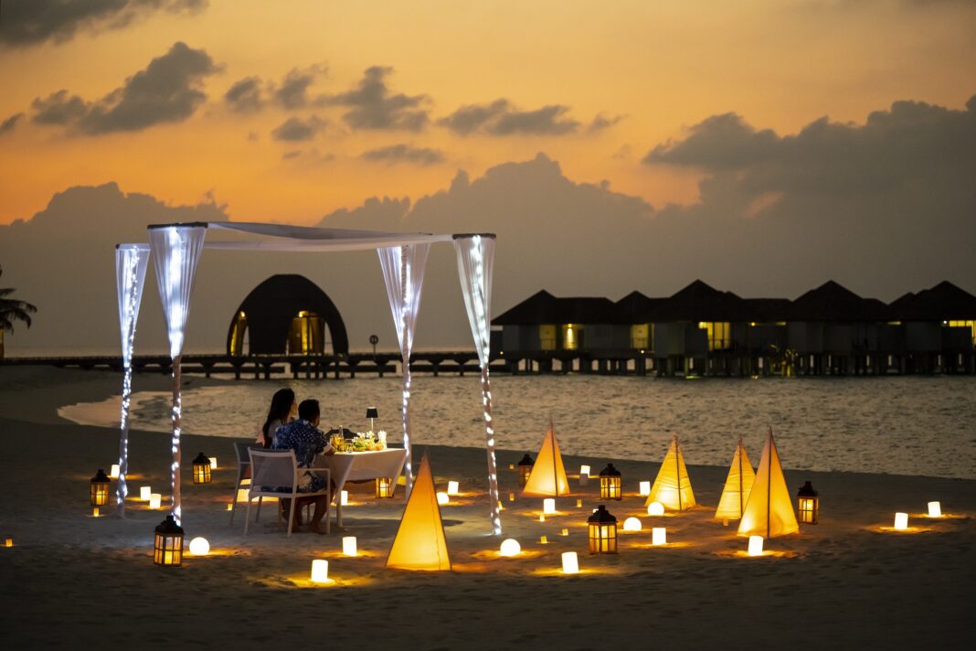 Ein Paar am Strand bei Dämmerung, umgeben von stimmungsvoller Beleuchtung.