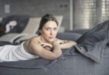 Frau liegt in weißes Handtuch gehüllt auf einem Tagesbett im Spa-Bereich.