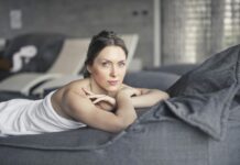 Wellness-Trends 2024 – Die Wellnessbranche erlebt einen dynamischen Wandel Frau liegt in weißes Handtuch gehüllt auf einem Tagesbett im Spa-Bereich.