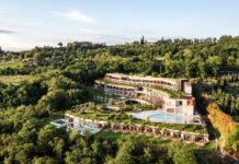 Garten der Sinne – A-ROSA eröffnet erstes Hotel in Italien Blick auf ein Hotelgebäude mit Pool, eingebettet in einen grünen Hügel.