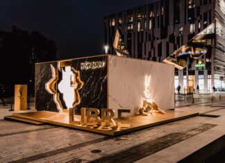 YSL Beauté eröffnet Pop-up Boutique in Düsseldorf Aufnahme bei Nacht. In Braun- und Goldtönen gestalteter Container, abgestellt auf einem Platz mit einer HÄuserfassade im Hintergrund.
