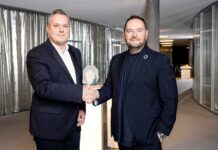 COTY und SWAROVSKI vereinbaren eine langfristige Beautylizenz Zwei Männer in dunklen Anzügen geben sich die Hand.