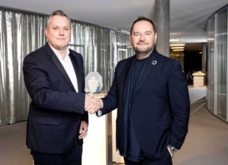 COTY und SWAROVSKI vereinbaren eine langfristige Beautylizenz Zwei Männer in dunklen Anzügen geben sich die Hand.