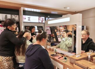 UNIQUE by baslerbeauty veranstaltet Schminkschule für sehbehinderte Frauen Mehrere Frauen sitzen sich in einer Parümerie gegenüber. Eine der Frauen wird von einer weiteren Frau geschminkt.