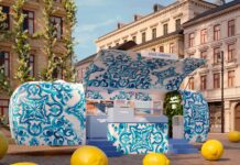 Dolce&Gabbana lädt zur Light Blue Summer Tour Türkis bemalter Anhänger steht vor einem Gebäude. Im Vordergrund liegen mehrere große Zitronen.