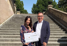 Inspira spendet für krebskranke Kinder Frau und Mann bei Spendenscheck-Übergabe auf großer Freitreppe