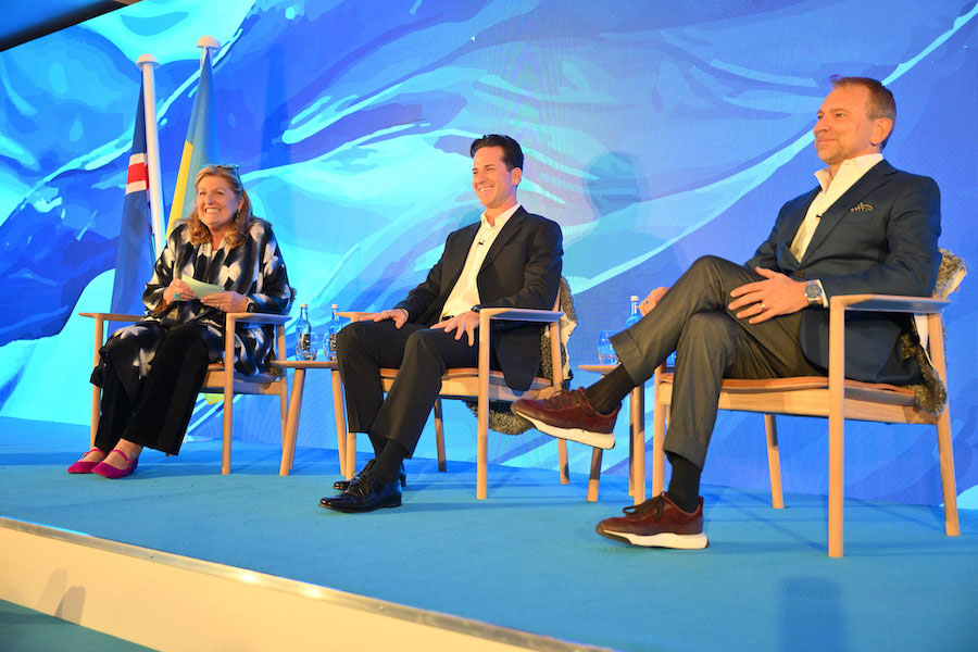 Panel-Diskussion mit drei Business-Casual gekleideten Teilnehmern auf Stühlen sitzend