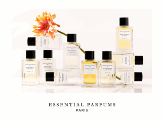 NOBILIS GROUP und Essential Parfums verkünden Vertriebspartnerschaft Gefüllte Flakons neben- und aufeinander angeordnet. Eine Gerbera mit orangefarbener Blüte ist dazwischen drapiert.