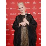 Verleihung der SPA Awards in Baden-Baden Frau mit kurzen blonden Haaren hält eine goldene Trophäe in der Hand. Sie steht vor einem roten Hintergrund