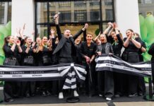 Sephora eröffnet ersten eigenen Store in München Mitarbeitende von Sephora, alle dunkel gekleidet, stehen mit einem Banner vor dem Shop