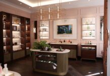 The House of Creed – Erste Flagship Boutique in Deutschland Ladengeschäft mit Einrichtung in dunkler Brauntönen, hellen Wänden. Auf dem Verkaufstresen und in den Regalen stehen bunte Flakons.