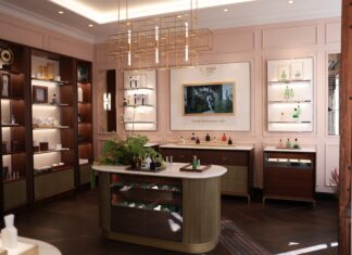 The House of Creed – Erste Flagship Boutique in Deutschland Ladengeschäft mit Einrichtung in dunkler Brauntönen, hellen Wänden. Auf dem Verkaufstresen und in den Regalen stehen bunte Flakons.