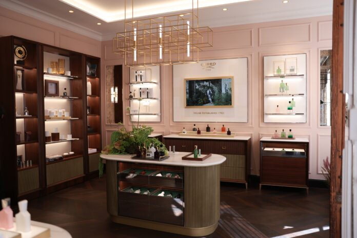 Ladengeschäft mit Einrichtung in dunkler Brauntönen, hellen Wänden. Auf dem Verkaufstresen und in den Regalen stehen bunte Flakons.