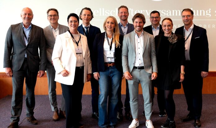 Eine Gruppe aus sieben Männern und drei Frauen sieht in die Kamera. Alle gekleidet mit Blazer oder Anzug.
