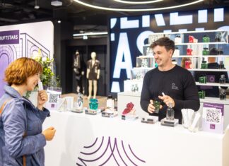 DUFTSTARS: Publikumspreis zum Anfassen Junger Mann in dunklem Shirt vor einem Regal mit vielen Duftflakons beim Beraten einer Kundin.