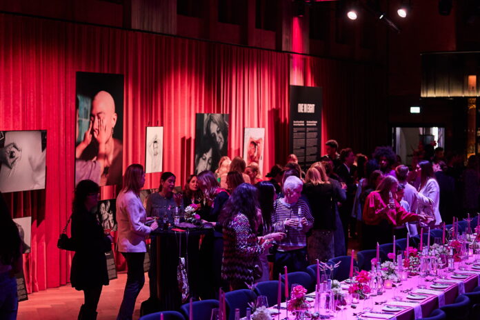 Ausstellungsfläche mit Besuchern. Die Farben Rosa und Lila dominieren